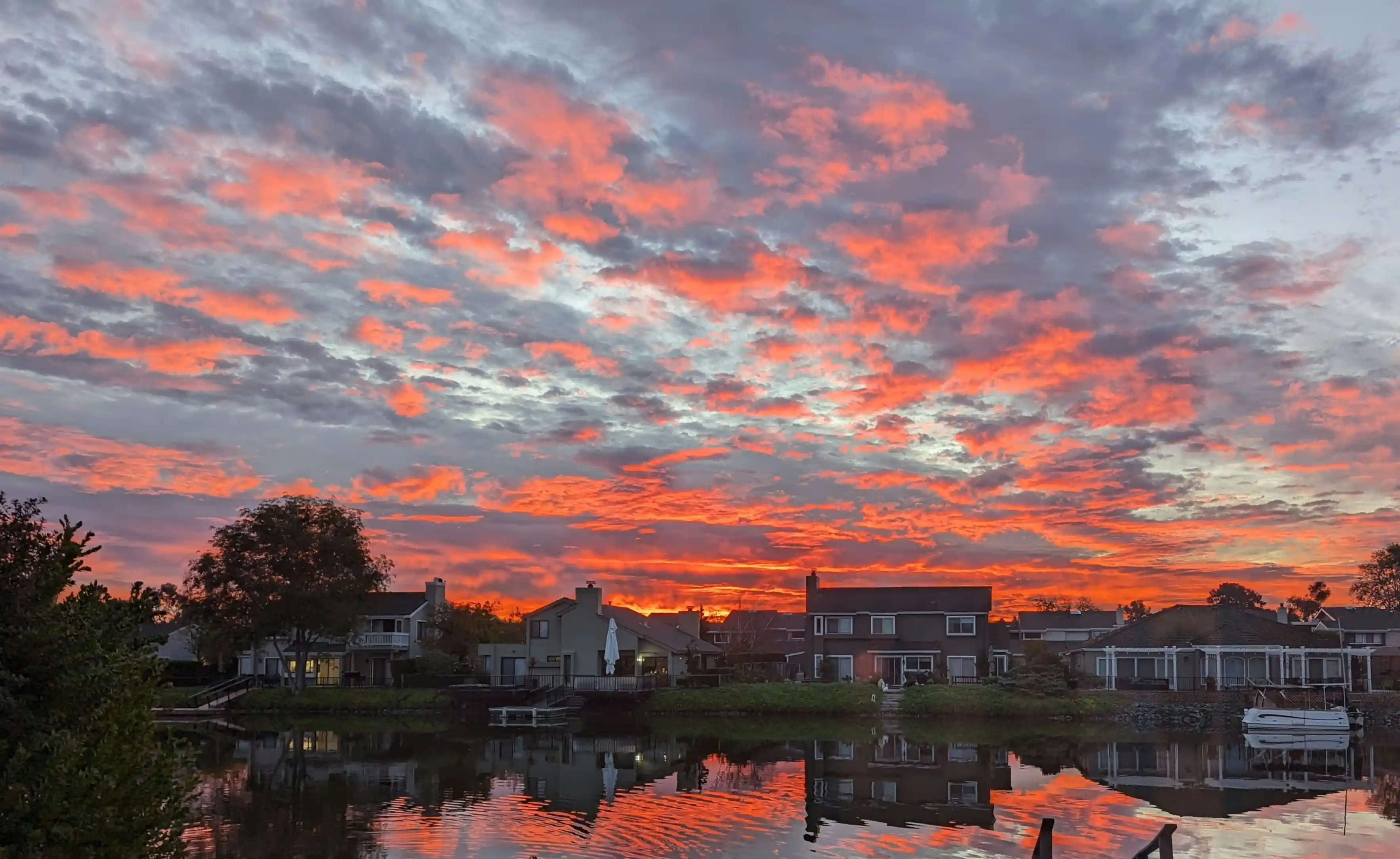 A colorful sunset behind a row of houses reflected in water